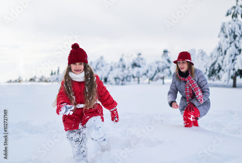 Mother walks with her daughter in  snowy winter park