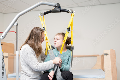 Disability a disabled child being cared for / Disability a disabled child being cared for by a special needs carer using specialist lifting equipment