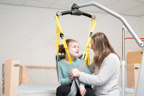 Disability a disabled child being cared for / Disability a disabled child being cared for by a special needs carer using specialist lifting equipment
