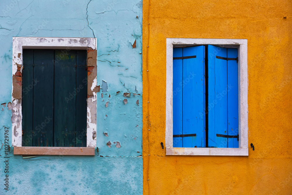 Old walls of blue and orange with the windows closed shutters, Burano, Venice