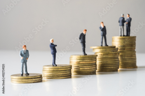 Businessmen standing on coins stack.