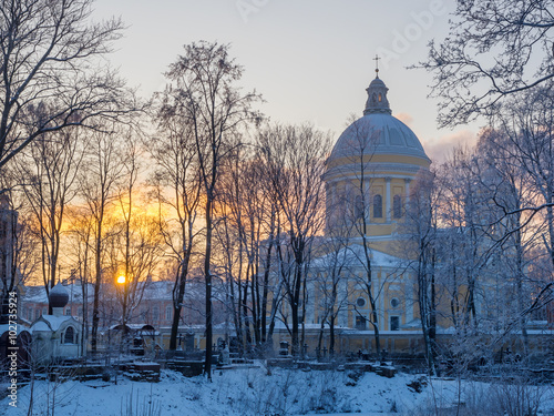 St. Petersburg in the winter. Alexander Nevsky Lavra through the trees on a background of a frosty sunset from the Nikolsky cemetery