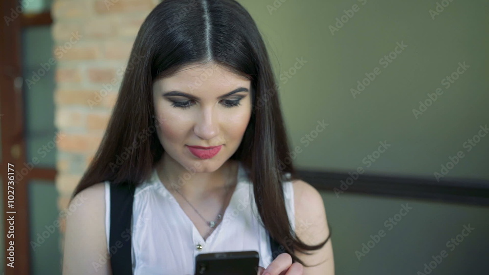 The girl is sitting in a cafe using phone The girl is sitting in a cafe using phone