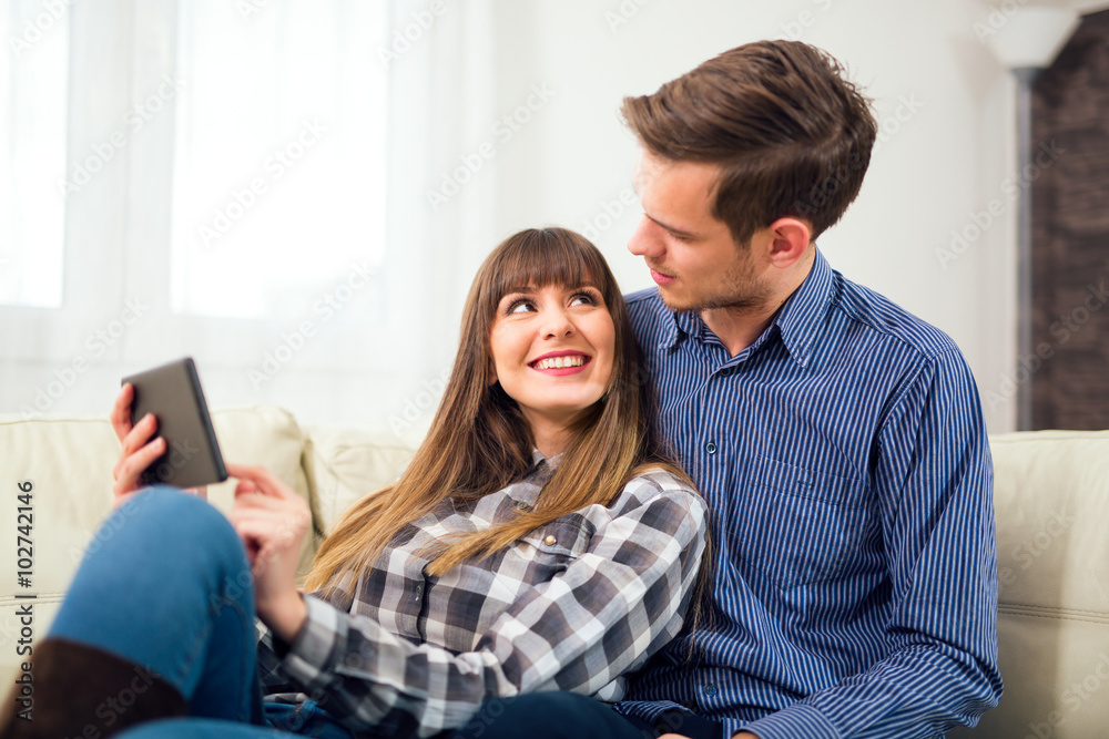 Attractive couple using tablet together on sofa at home. Attractive couple using tablet together on sofa at home.