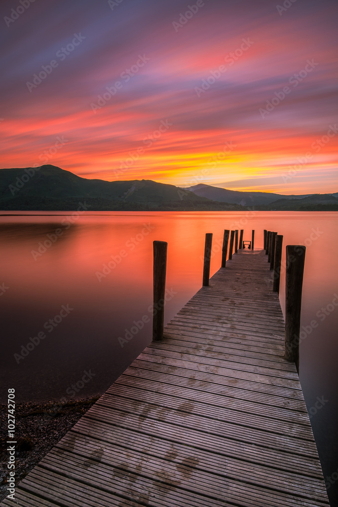 Vibrant orange/red long exposure sunset over Derwentwater in the English Lake District. The tourist-popular Ashness jetty can be seen in the foreground.