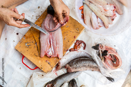 Human cleaning and filleting a fresh fish for cooking. Top view