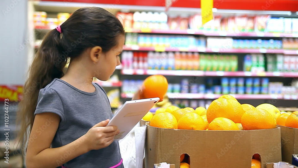 girl teen with tablet in the supermarket to buy orange girl teen with tablet in the supermarket to buy orange