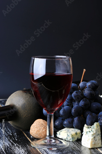 glass of wine grapes alcohol bottle cheese worn wooden background retro vintage style