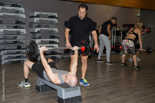 Man and trainer at exercise in gym with dumbbell weights