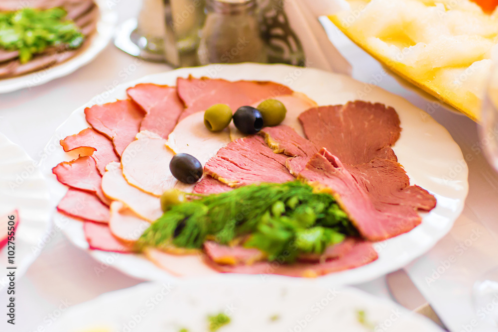 Serving of delicious smoked ham and  appetizers displayed on a plate on a buffet at a party or reception