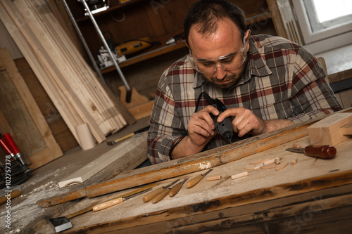 Konstfotografi Carpenter carving wood with engraver tool
