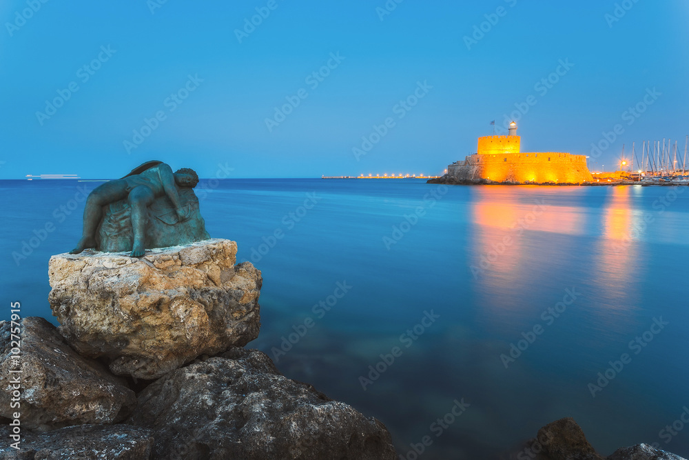Fototapeta premium Sculpture of an angel on a background of the fortress of St. Nicholas. Rhodes Island. Greece
