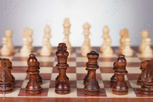 chess board with black and white figures over grey background