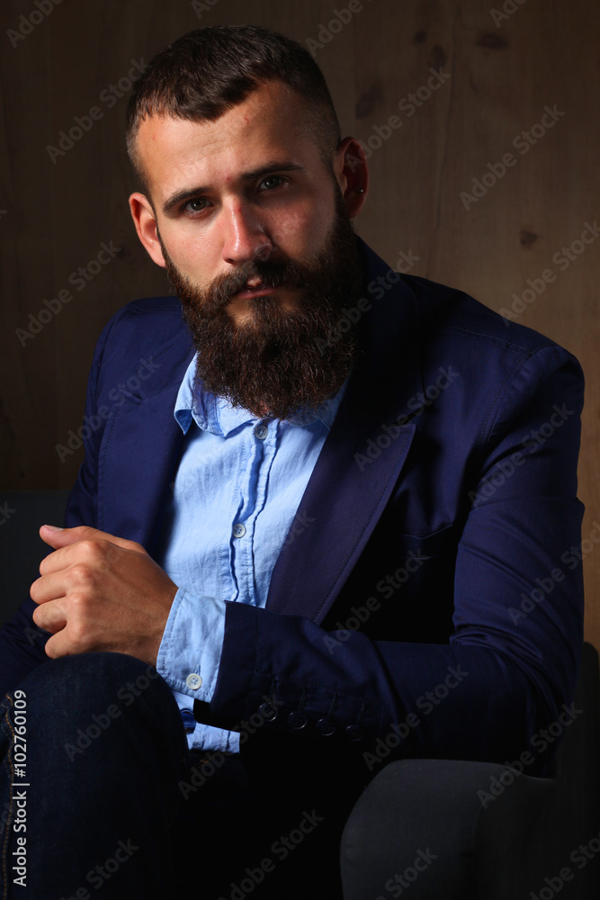Businessman sitting the sofa in office lobby, isolated on dark background Businessman sitting the sofa in office lobby, isolated on dark background