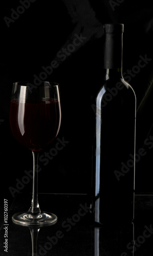 Elegant wine glass and a wine bottle in black background