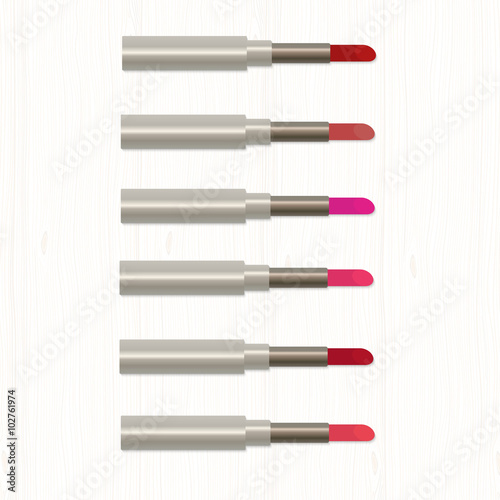 Set of realistic colored lipsticks on white wooden table