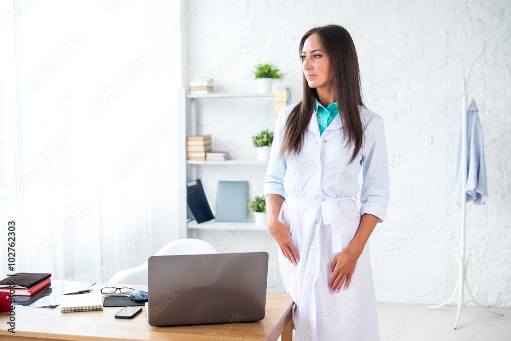 Portrait of young woman doctor with white coat standing in medical office Portrait of young woman doctor with white coat standing in medical office