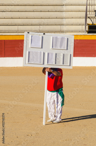 Unrecognizable man holding empty scoreboard in the bullring