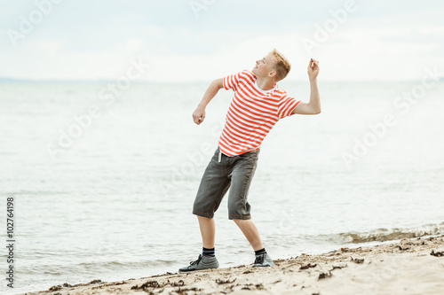 Teenage boy throwing stones into the ocean