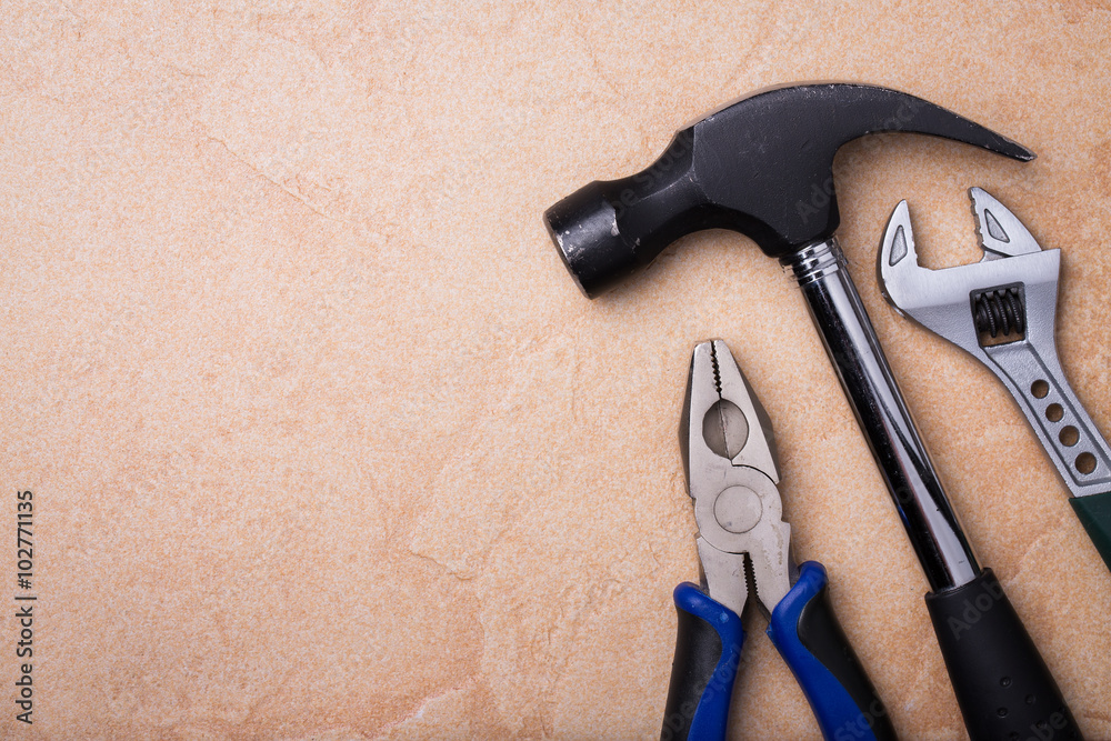 Hammer, wrench and pliers on a stone surface with space for text Hammer, wrench and pliers on a stone surface with space for text
