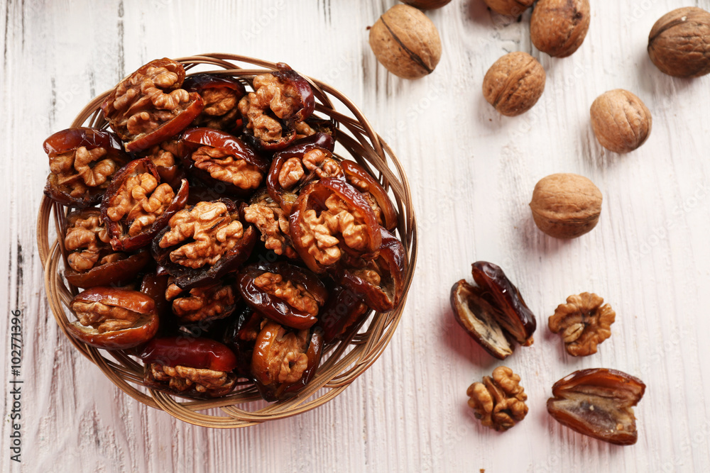 Walnut and date fruit in plate on wooden table, close-up Walnut and date fruit in plate on wooden table, close-up