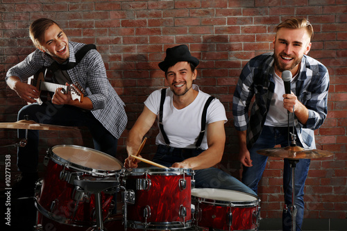 Musicians playing the drums on brick wall background photo