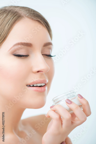 Beautiful woman holding face cream 