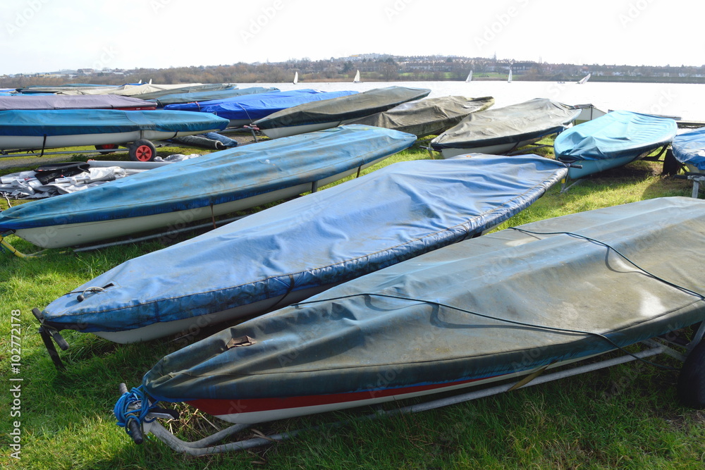 Fototapeta premium Row of sailing boats stored next to the lake