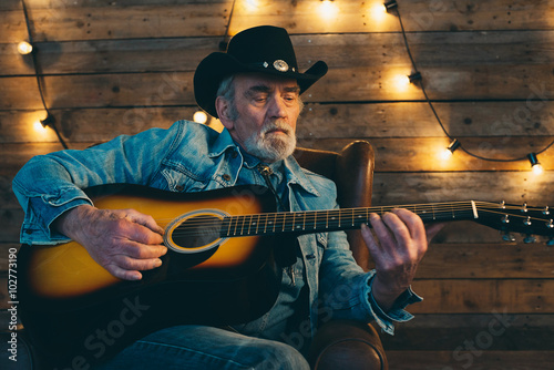 Guitar playing senior country and western musician with beard si
