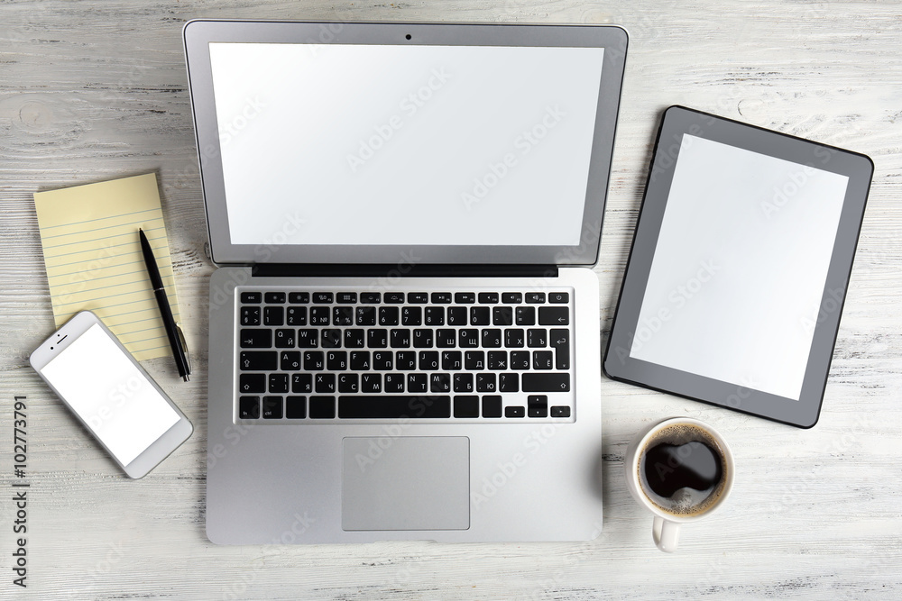 Modern laptop, mobile phone, tablet, coffee cup and notebook on white wooden background Modern laptop, mobile phone, tablet, coffee cup and notebook on white wooden background