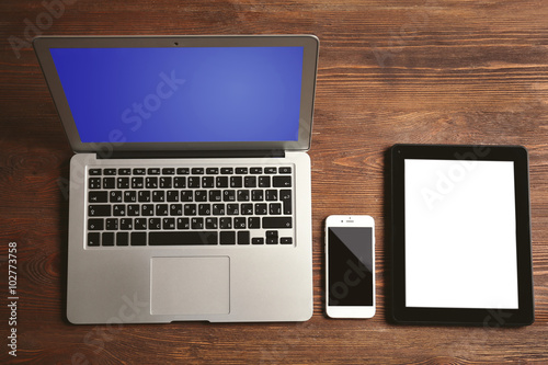 Modern laptop, mobile phone and tablet on wooden background