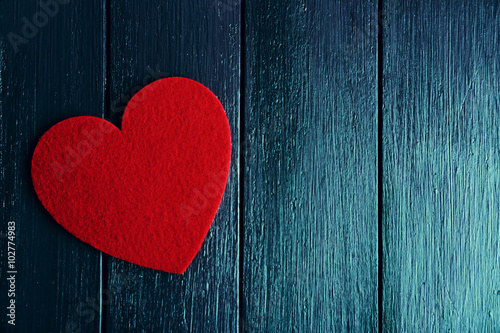 Red felt heart on purple wooden background