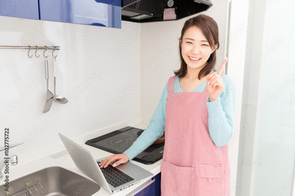 パソコンを見ながら料理をする女性 パソコンを見ながら料理をする女性