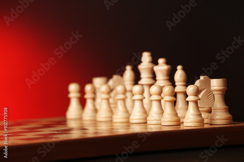Chess pieces and game board on dark red background