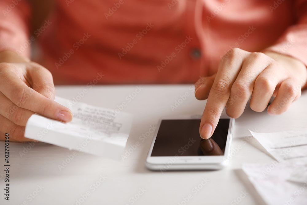 Woman with bills and smart phone at the table. Calculation of costs Woman with bills and smart phone at the table. Calculation of costs