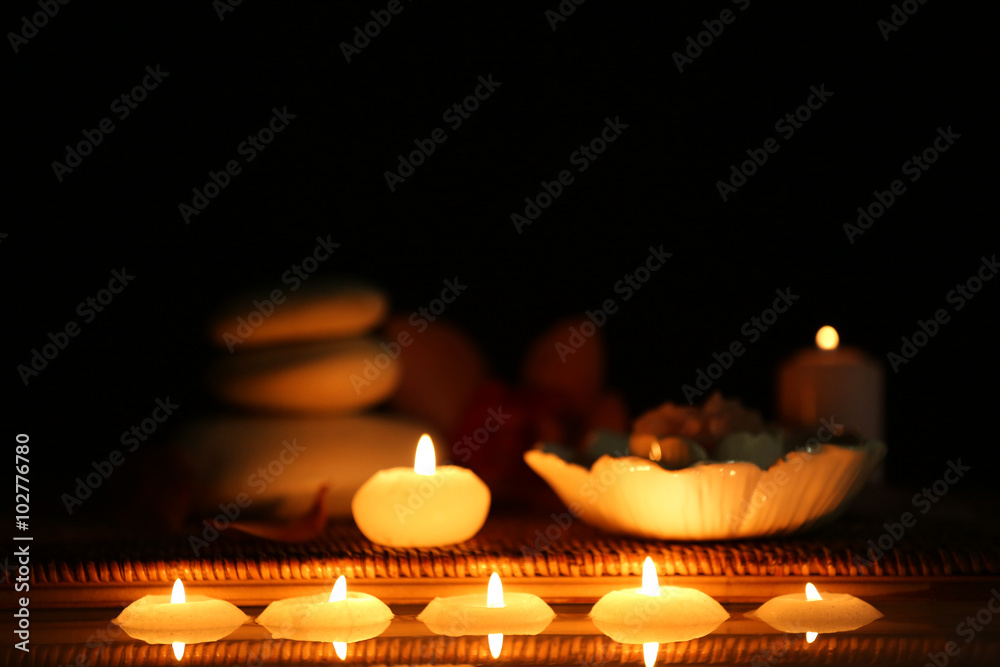 Spa still life with stones, candles and flowers in water on black background Spa still life with stones, candles and flowers in water on black background