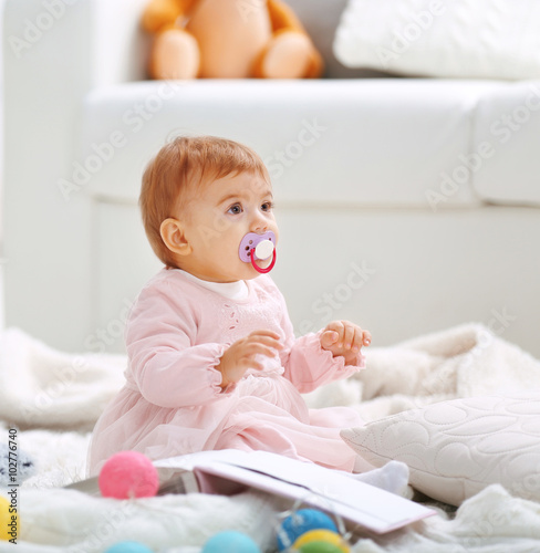 Tablou pe pânză Sweet baby girl with a soother playing on floor