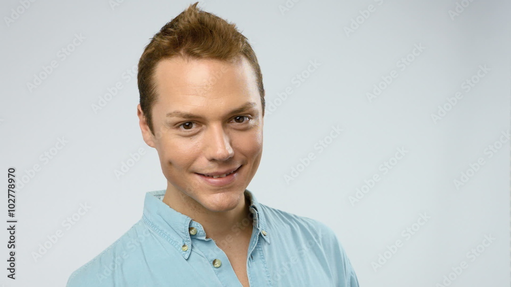 Young adult man turns his head, looks at camera and smiles. He looks confident and happy. Young adult man turns his head, looks at camera and smiles. He looks confident and happy.