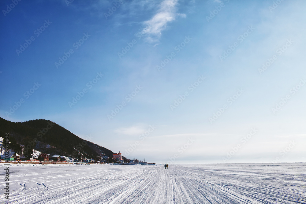 two people go away on frozen lake Baikal