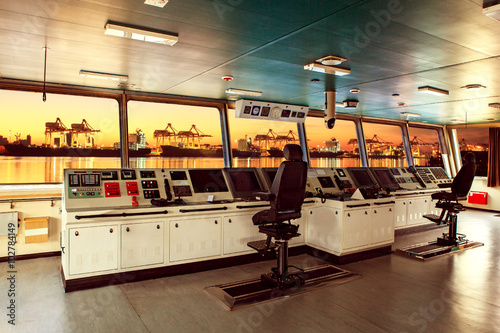 wheelhouse control board of modern industry ship approaching to photo