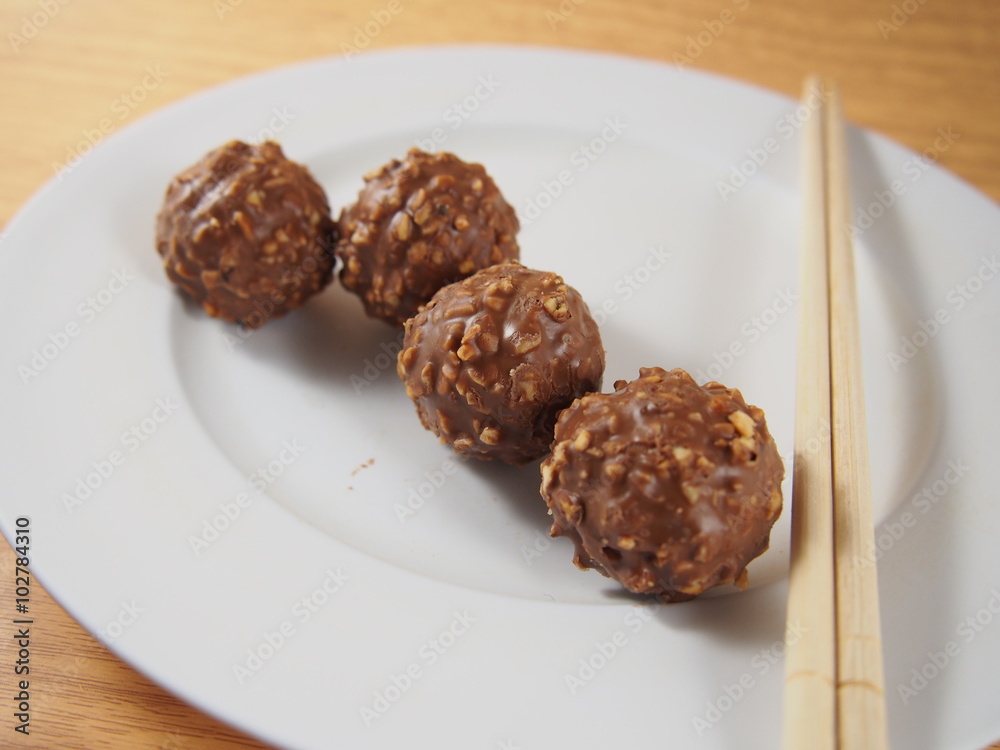 Milk chocolate balls with crushed almond and peanuts on white dish Milk chocolate balls with crushed almond and peanuts on white dish