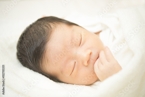 タオルに包まれて眠る新生児のアップ