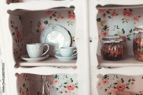 Foto Beautiful white vintage wardrobe with ceramic dishes hanging on the wall