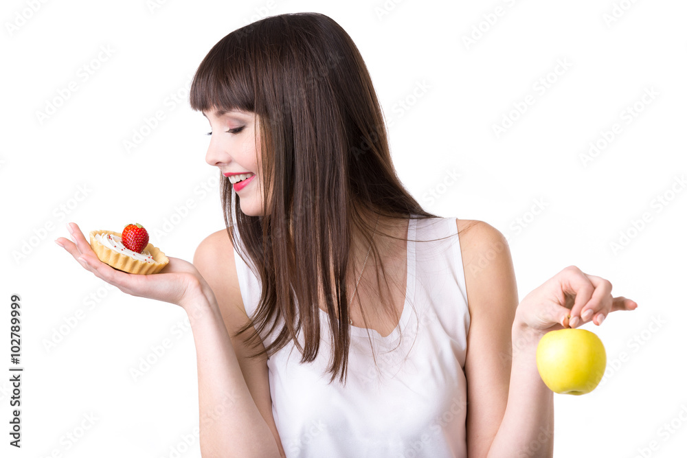 Young woman choosing cake instead of apple Young woman choosing cake instead of apple