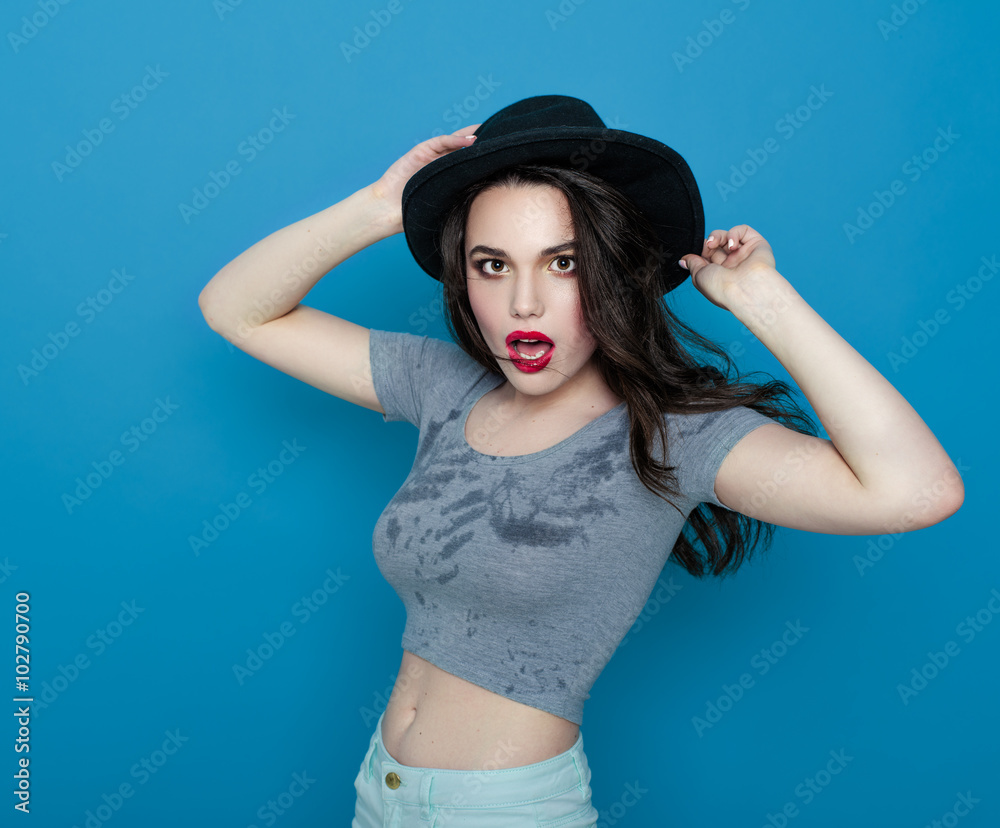 Girl in a hat and in a wet t-shirt on a blue background. Girl in a hat and in a wet t-shirt on a blue background.