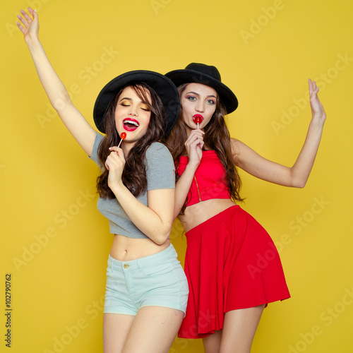 Two young smiling pretty beautiful girls wearing hats holding ca