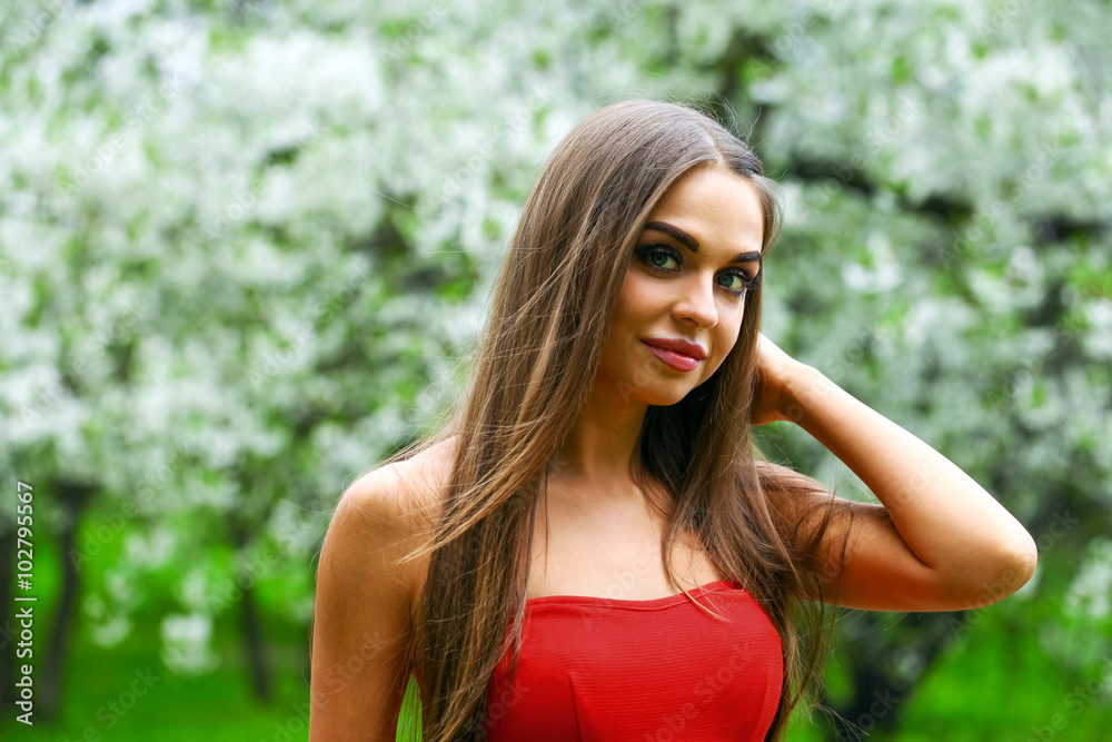 Happy young woman in red dress against the background spring flo