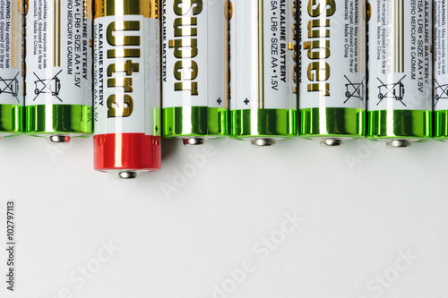 Batteries, row of alkaline battery AA size format with green top and one with red top, energy abstract background, selective focus  photo