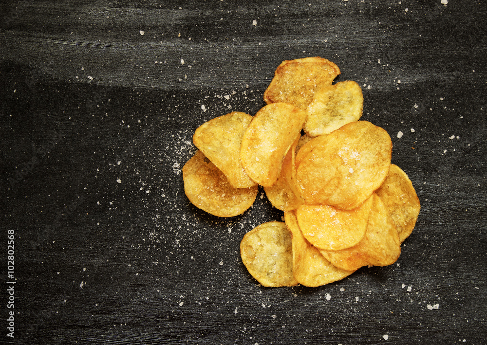 potato chips and salt on black background