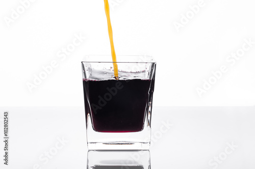 Orange juice pouring into glass with blackcurrant juice